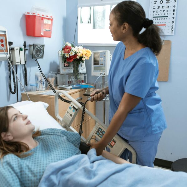 Nurse providing care to a patient in a hospital room with medical equipment.